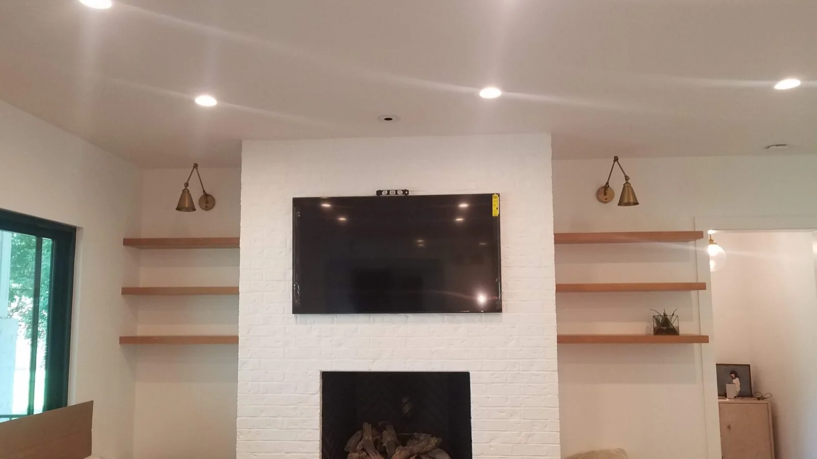 TV mounted above a fireplace between built-in shelves