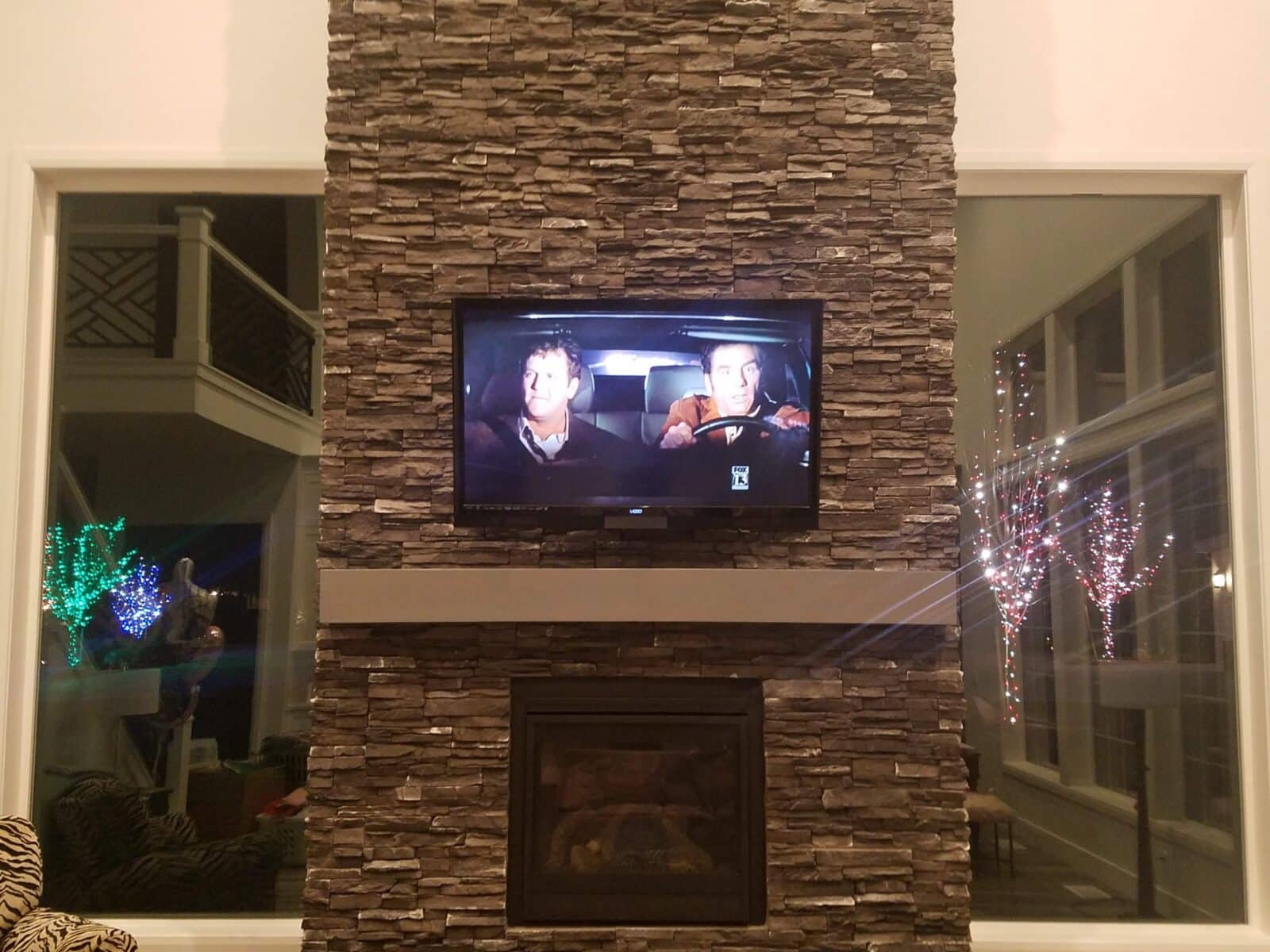 TV mounted above a floor-to-ceiling stone fireplace