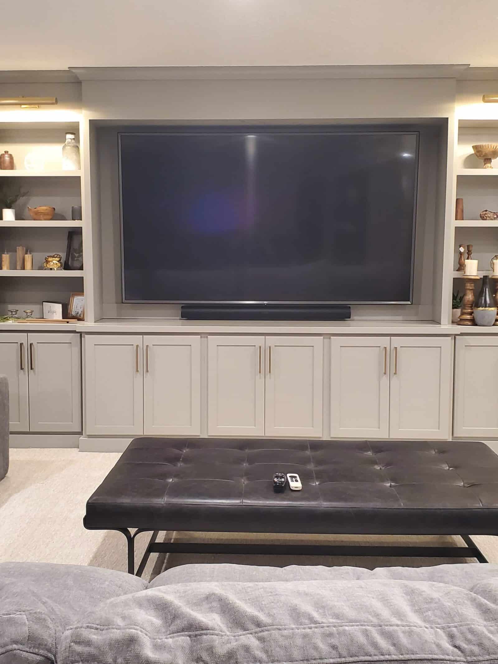 Large television and soundbar mounted above custom cabinetry